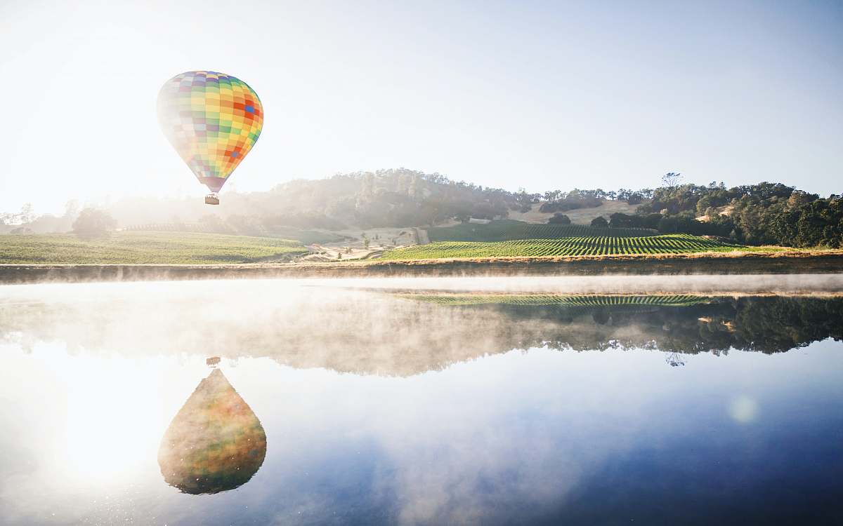 balloon hot air balloon floating in mid air above body of water aircraft